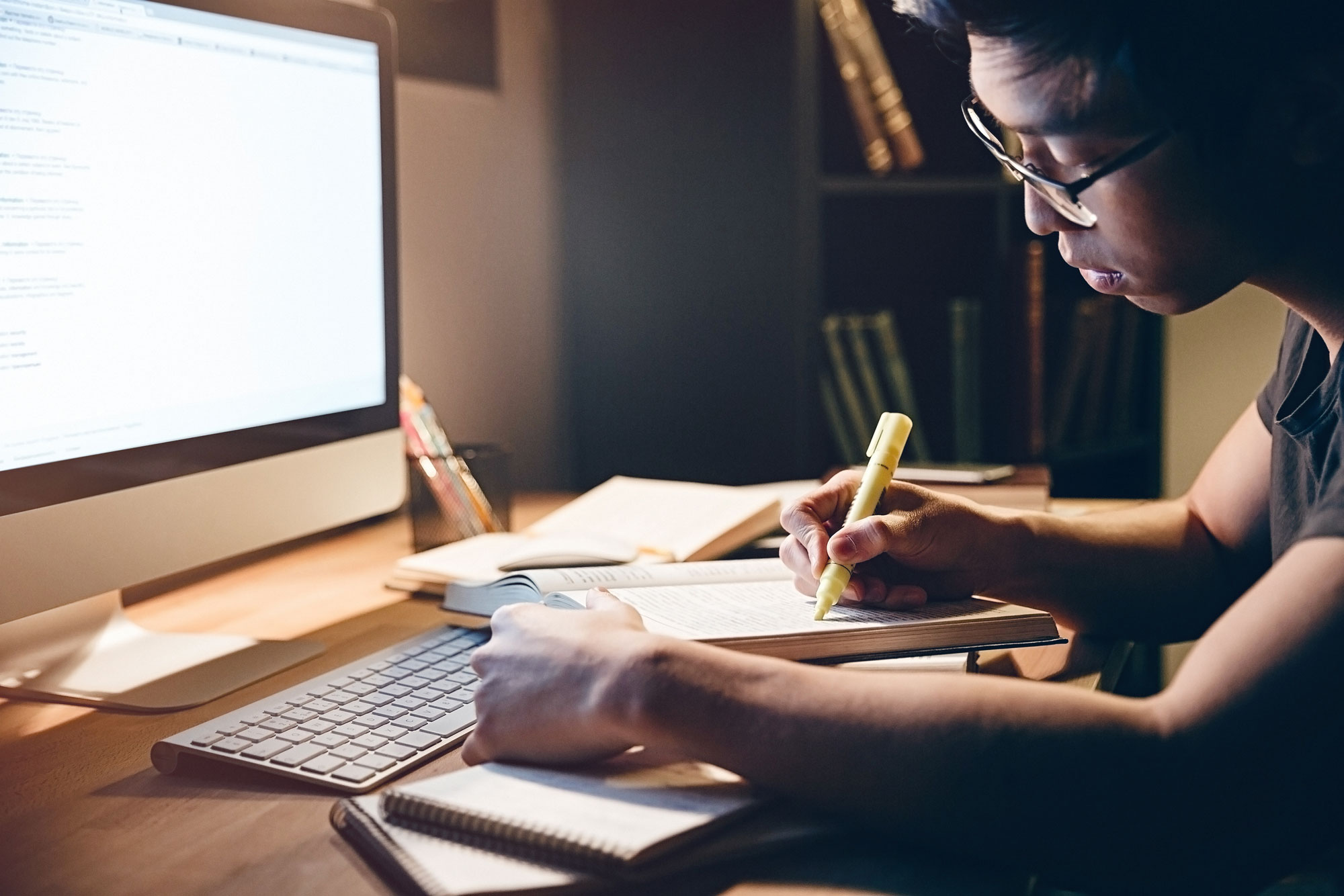 A student studying from home with computer and books