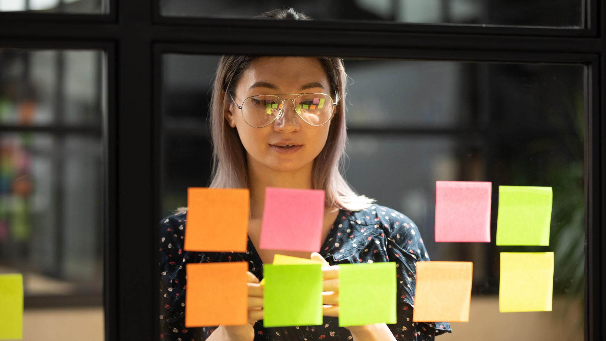 Student being productive by writing ideas on sticky notes as part of university’s counselling program