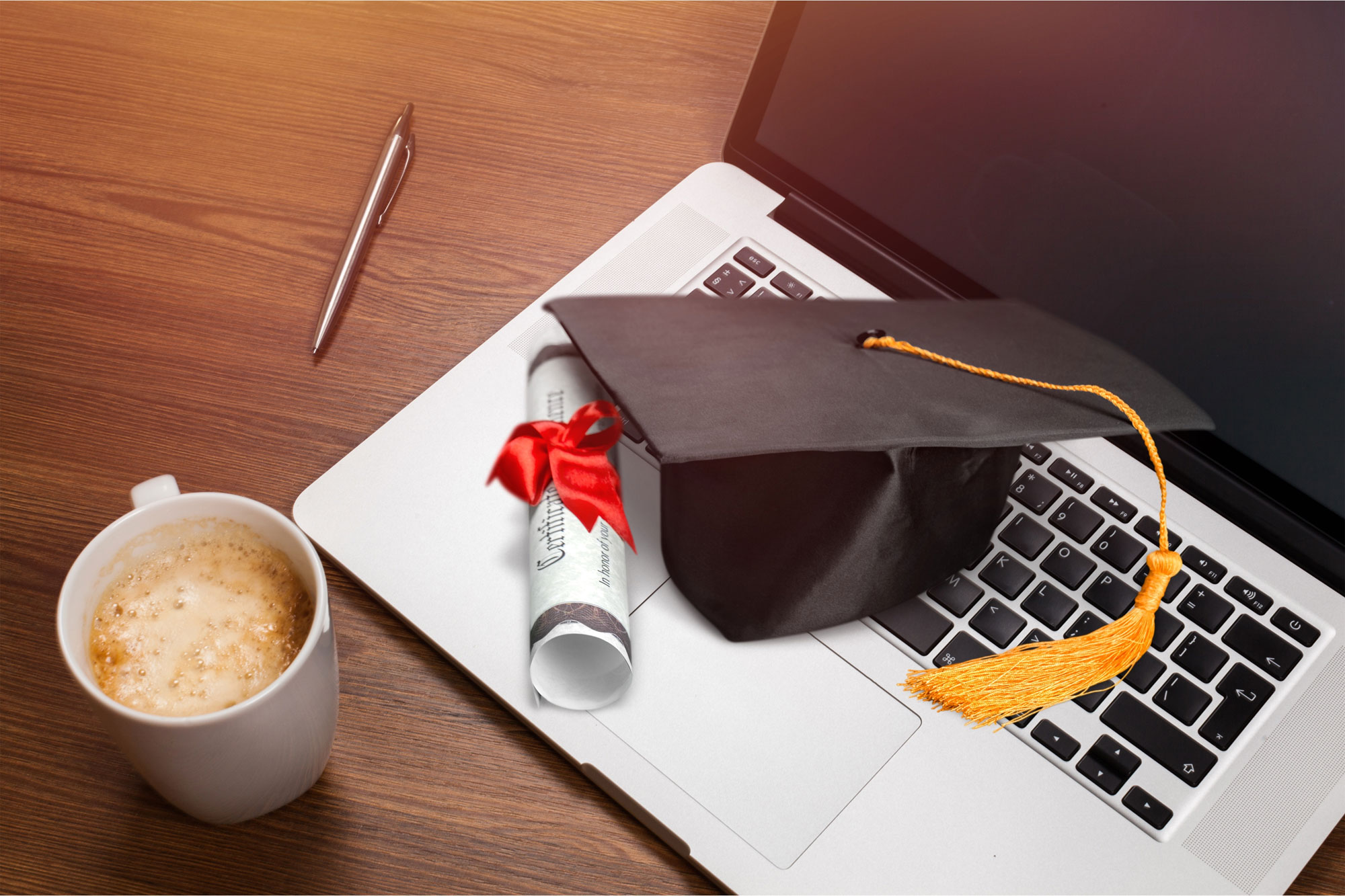 A laptop with graduation cap and scroll symbolizing online degree 